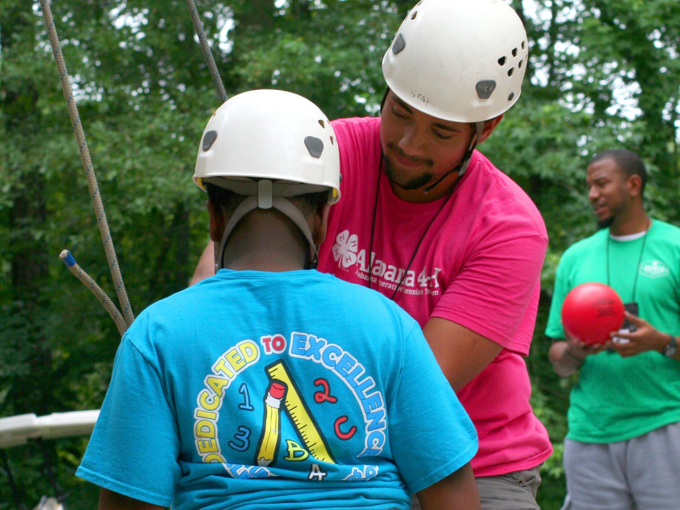 youth being assisted into a safty harness for wall climbing